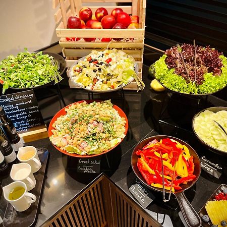 Апарт отель Royal Tulip Warsaw Centre Экстерьер фото The photo shows a well-arranged salad bar featuring a variety of fresh salads and ingredients. There are several bowls and dishes with different types of salads, including green salads and grain salads. 

1. **Green Salads**: There are multiple bowls