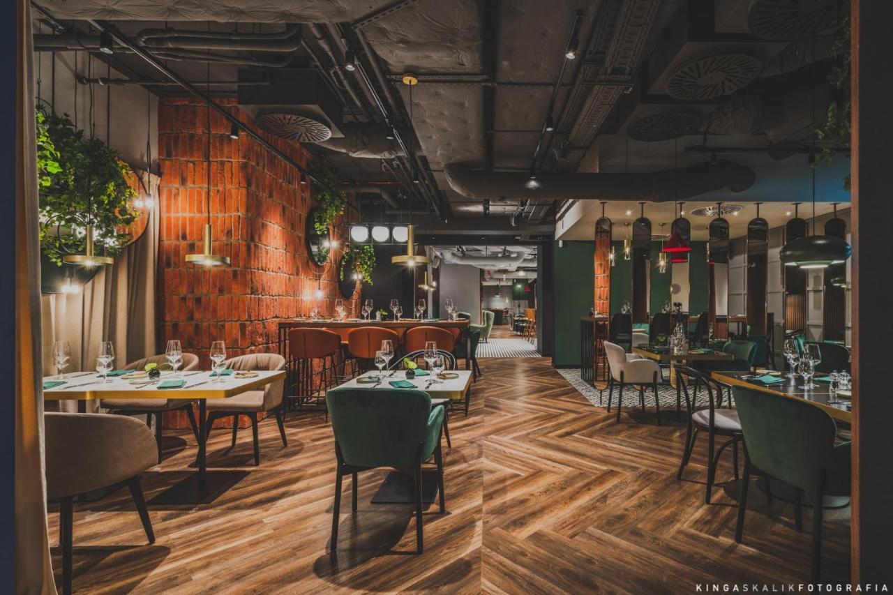 Апарт отель Royal Tulip Warsaw Centre Экстерьер фото The photo shows the interior of a modern restaurant. The design features a mix of wood and industrial elements, with a warm and inviting atmosphere. There are wooden floors laid in a herringbone pattern, and the walls have a combination of brick and 
