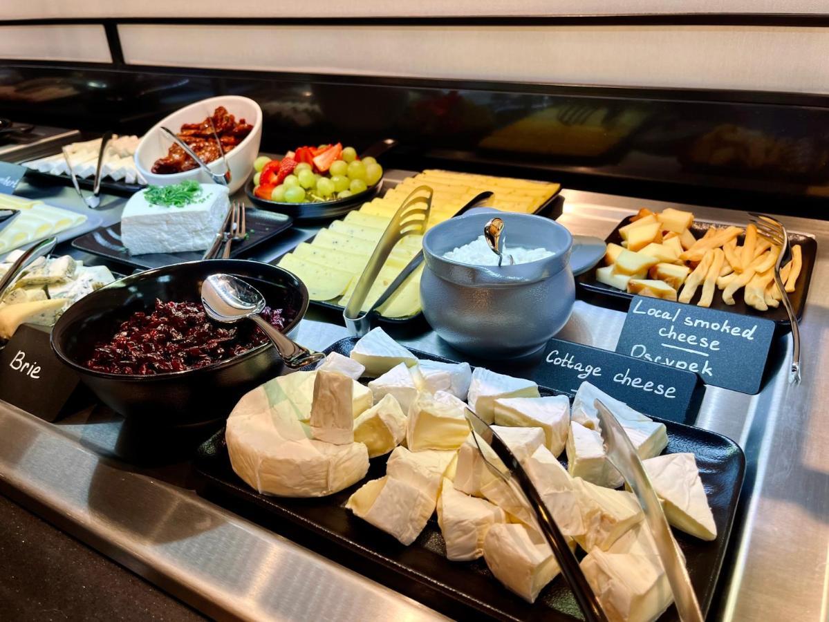 Апарт отель Royal Tulip Warsaw Centre Экстерьер фото The photo shows a variety of cheeses and accompaniments arranged on a buffet display. There are several types of cheese, including Brie and a soft cheese that appears to be cottage cheese. There's also a bowl of dark-colored cheese, likely a spread. 