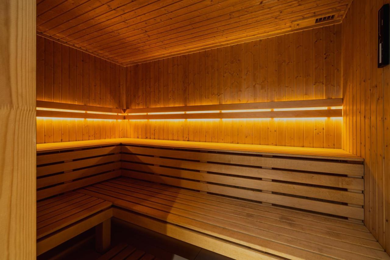 Апарт отель Royal Tulip Warsaw Centre Экстерьер фото The photo shows the interior of a sauna. It features wooden walls and benches, creating a warm and cozy environment. The lighting is dim but highlights the wood's natural grain, contributing to a relaxing atmosphere. The design includes benches that 