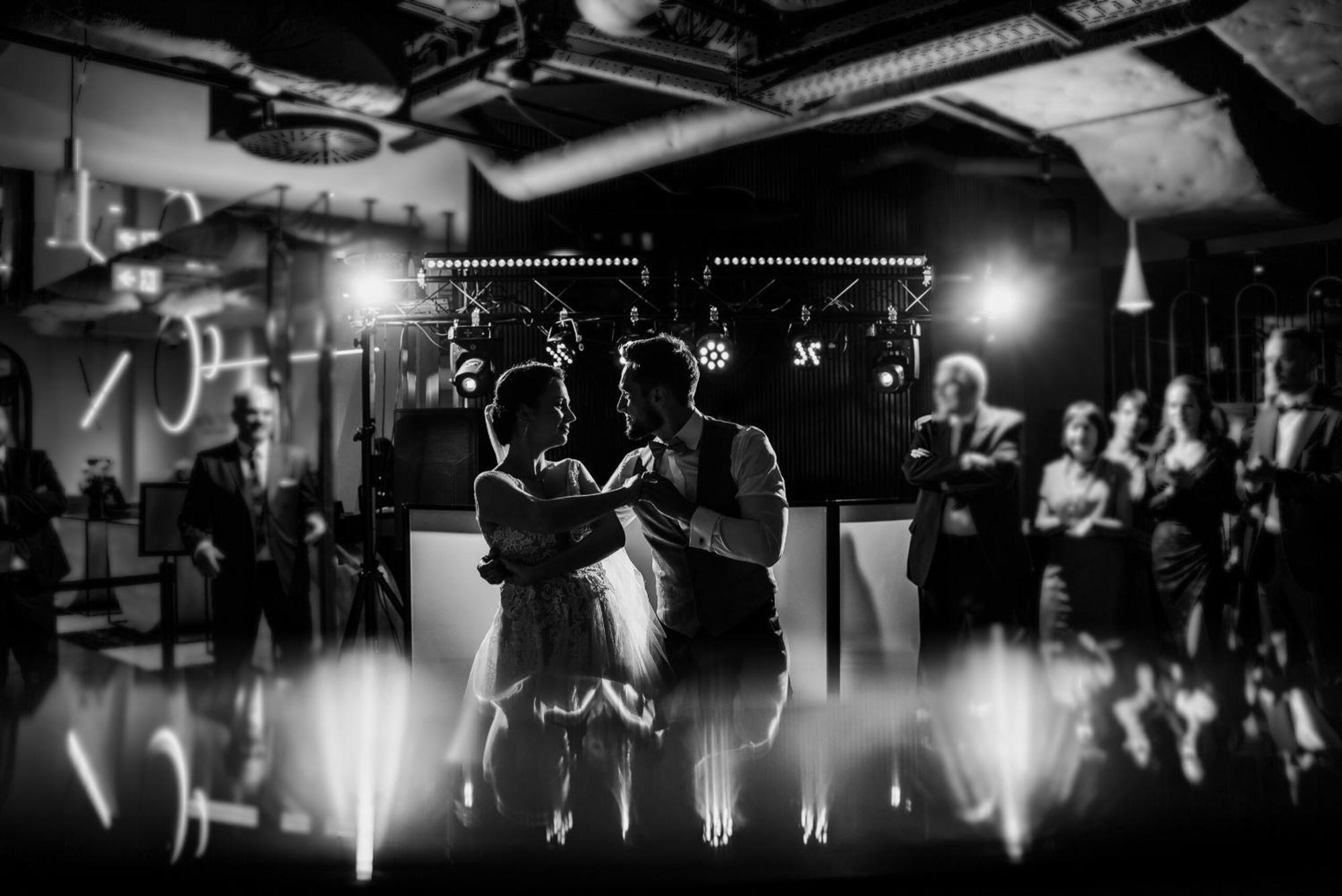 Апарт отель Royal Tulip Warsaw Centre Экстерьер фото The photo depicts a couple dancing together in an elegant setting, likely during a celebration such as a wedding. The scene is captured in black and white, emphasizing the intimate atmosphere. In the background, there are people observing and enjoyin